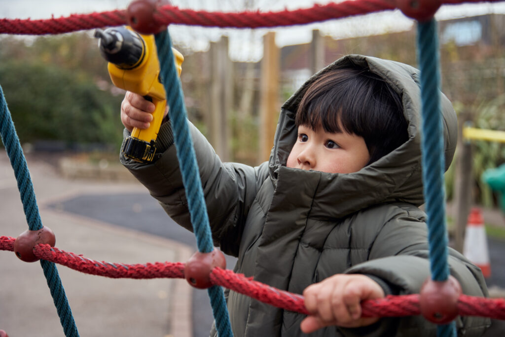 Nursery student playing on outdoor equipment
