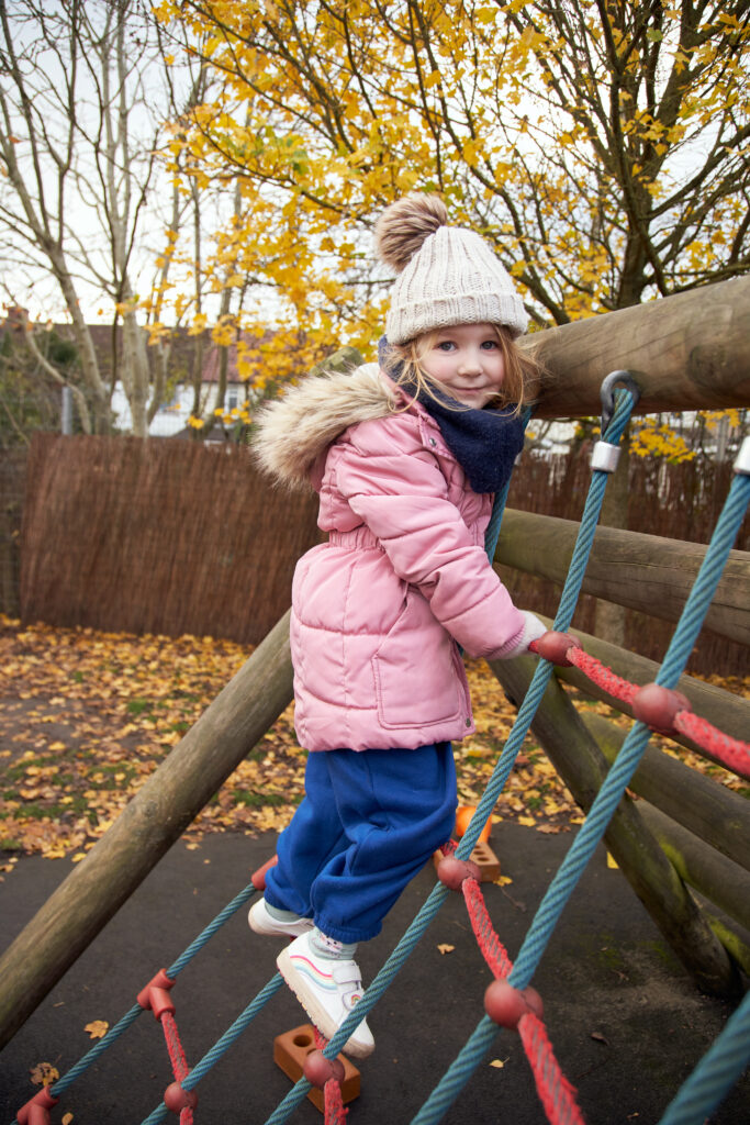 Nursery student playing on outdoor equipment