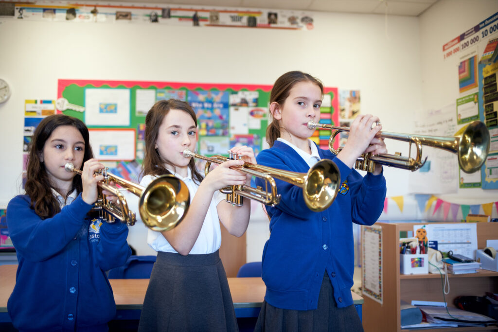 Three students playing the trumpet